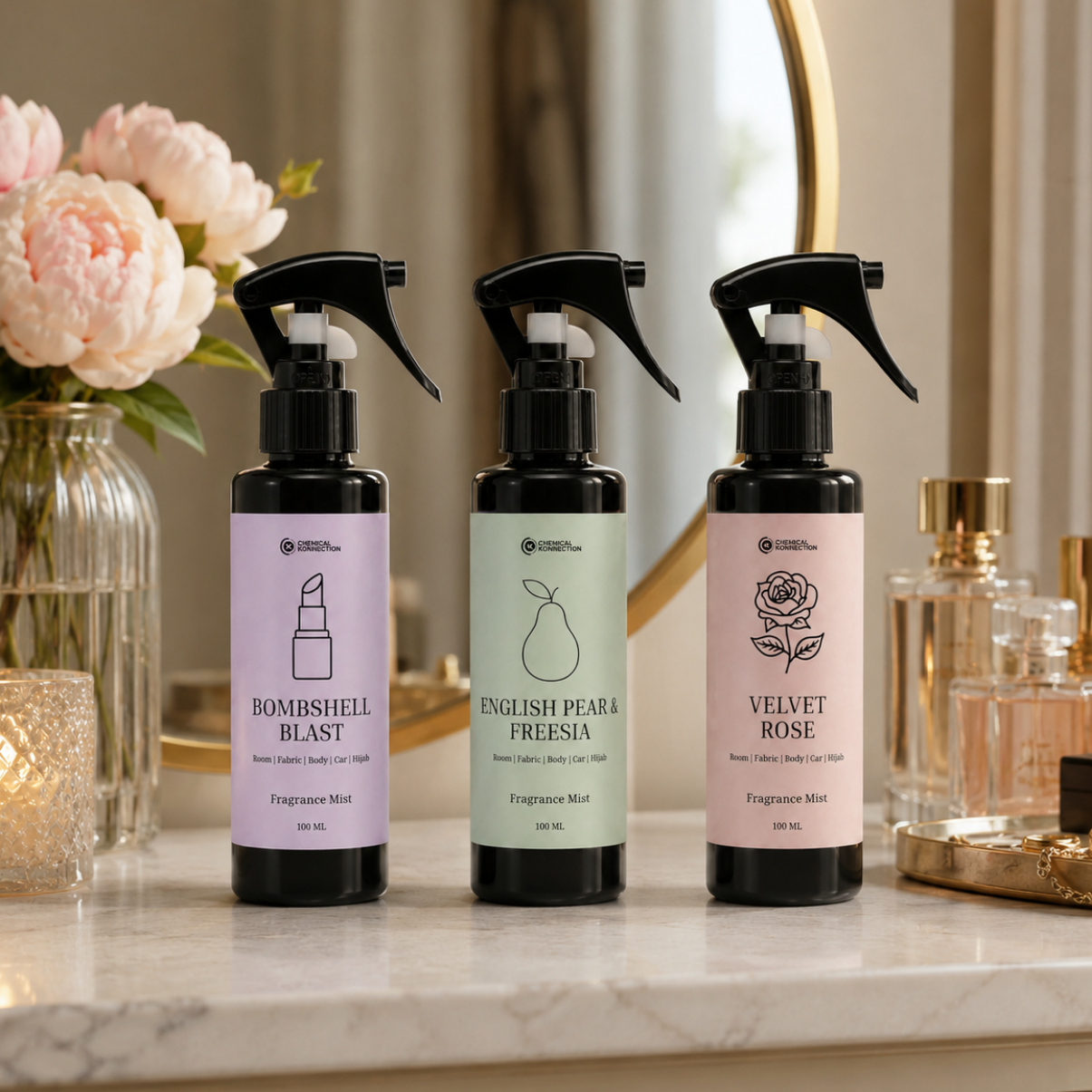 Three fragrance mist bottles with colorful labels on a marble surface.